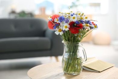Photo of Beautiful wildflowers in vase and book on wooden table at home. Space for text