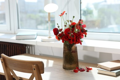 Photo of Beautiful poppy flowers in vase on wooden table at home