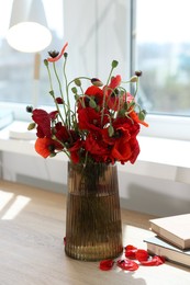 Photo of Beautiful poppy flowers in vase on wooden table at home