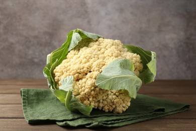 Photo of Fresh cauliflower with green leaves on wooden table, closeup