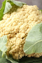Photo of Fresh cauliflower with green leaves on table, closeup