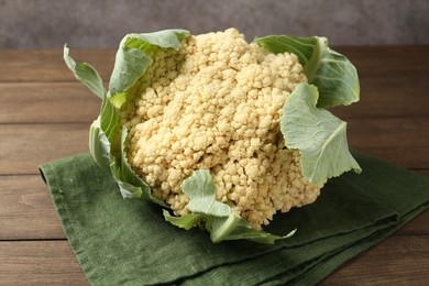Photo of Fresh cauliflower with green leaves on wooden table, closeup
