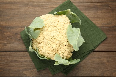 Photo of Fresh cauliflower with green leaves on wooden table, top view