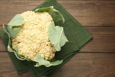 Photo of Fresh cauliflower with green leaves on wooden table, top view. Space for text