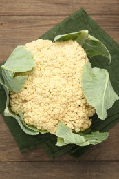 Photo of Fresh cauliflower with green leaves on wooden table, top view