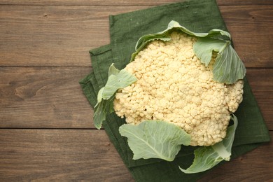 Photo of Fresh cauliflower with green leaves on wooden table, top view. Space for text
