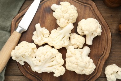 Photo of Fresh raw cauliflower florets and knife on wooden table, flat lay