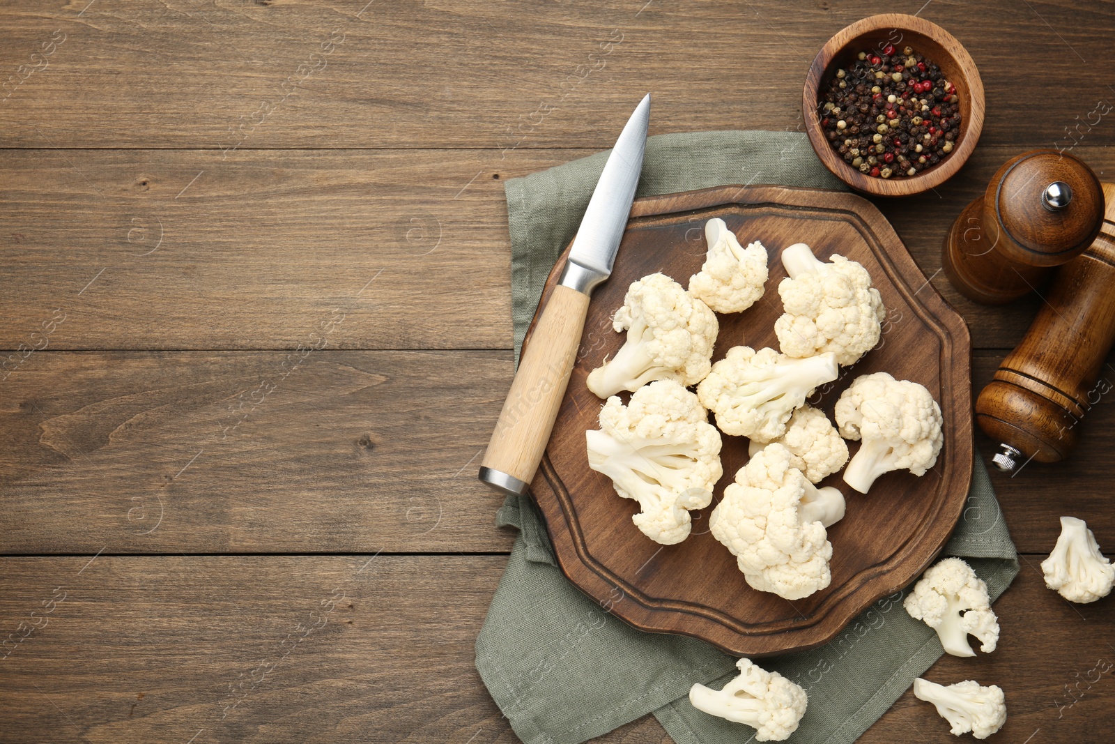 Photo of Fresh raw cauliflower florets, spices and knife on wooden table, flat lay. Space for text