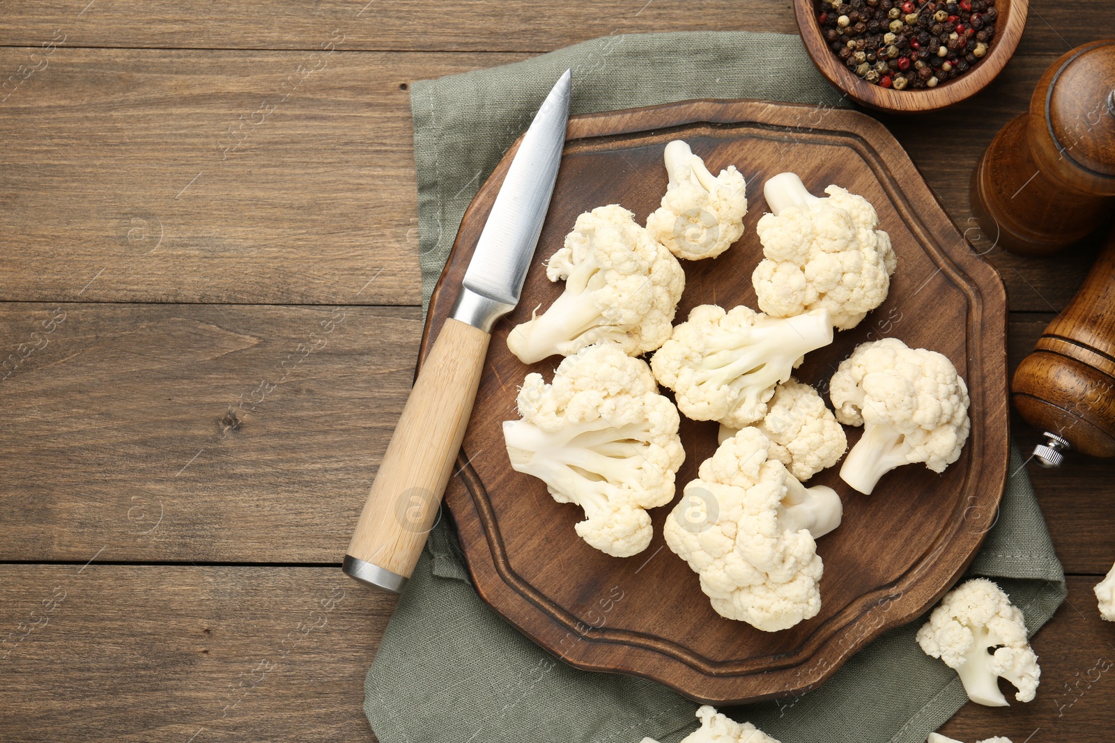 Photo of Fresh raw cauliflower florets, spices and knife on wooden table, flat lay. Space for text