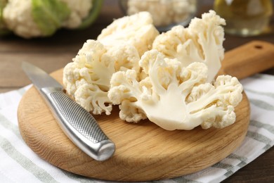 Photo of Fresh raw cauliflower florets and knife on table, closeup