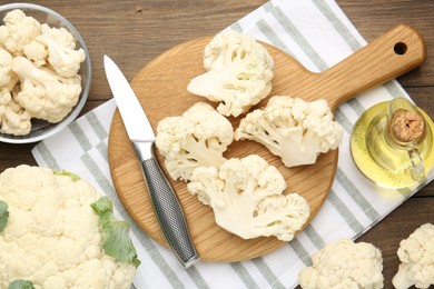 Photo of Fresh raw cauliflower florets, knife and oil on wooden table, flat lay