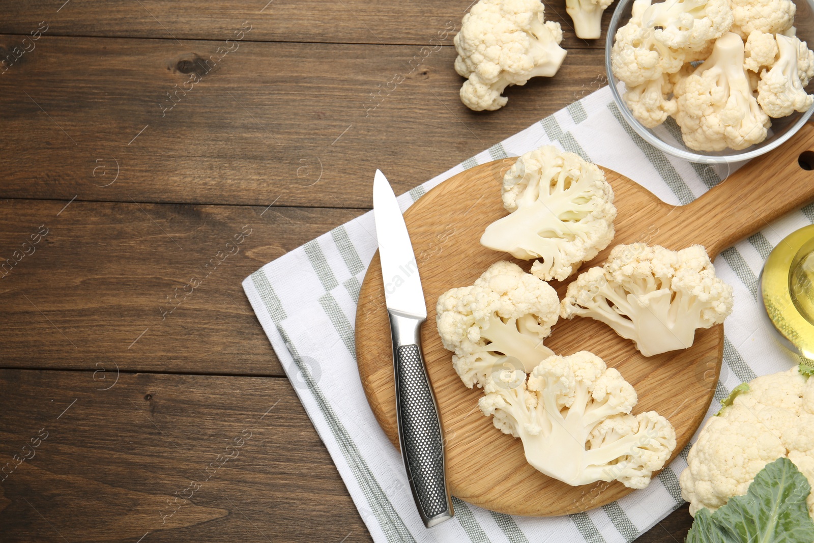 Photo of Fresh raw cauliflower florets and knife on wooden table, flat lay. Space for text