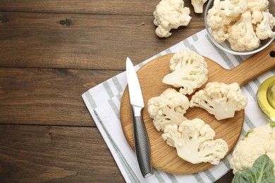 Photo of Fresh raw cauliflower florets and knife on wooden table, flat lay. Space for text