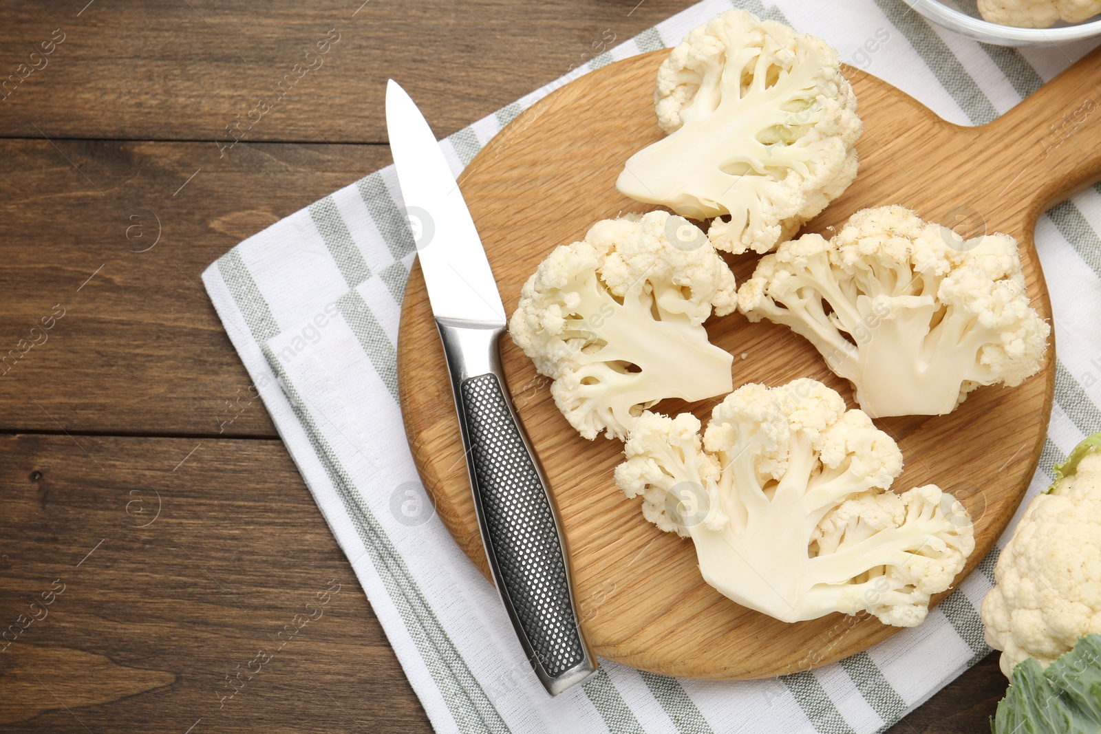 Photo of Fresh raw cauliflower florets and knife on wooden table, flat lay. Space for text
