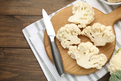 Photo of Fresh raw cauliflower florets and knife on wooden table, flat lay. Space for text