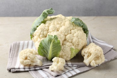 Photo of Fresh cauliflower with green leaves on light grey table, closeup
