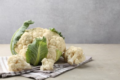 Photo of Fresh cauliflower with green leaves on light grey table, closeup. Space for text
