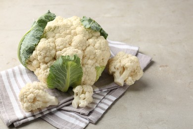 Photo of Fresh cauliflower with green leaves on light grey table, closeup. Space for text