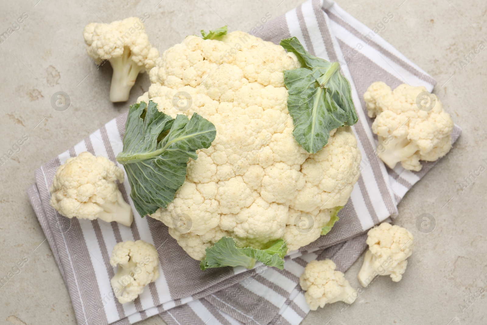 Photo of Fresh cauliflower with green leaves on light grey table, flat lay
