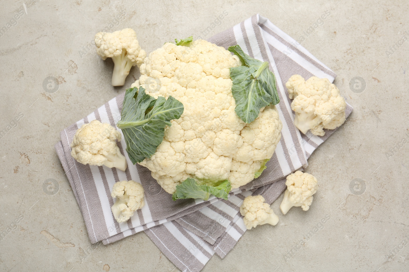 Photo of Fresh cauliflower with green leaves on light grey table, flat lay