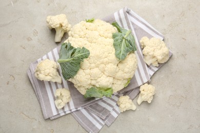Photo of Fresh cauliflower with green leaves on light grey table, flat lay