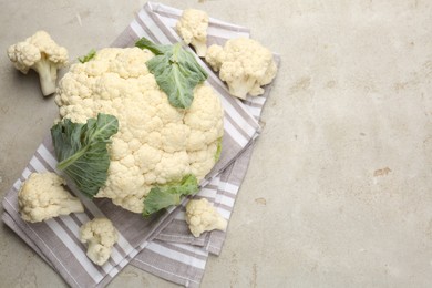 Photo of Fresh cauliflower with green leaves on light grey table, flat lay. Space for text