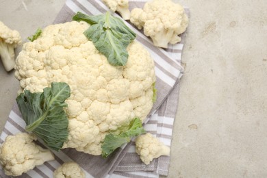 Photo of Fresh cauliflower with green leaves on light grey table, flat lay. Space for text
