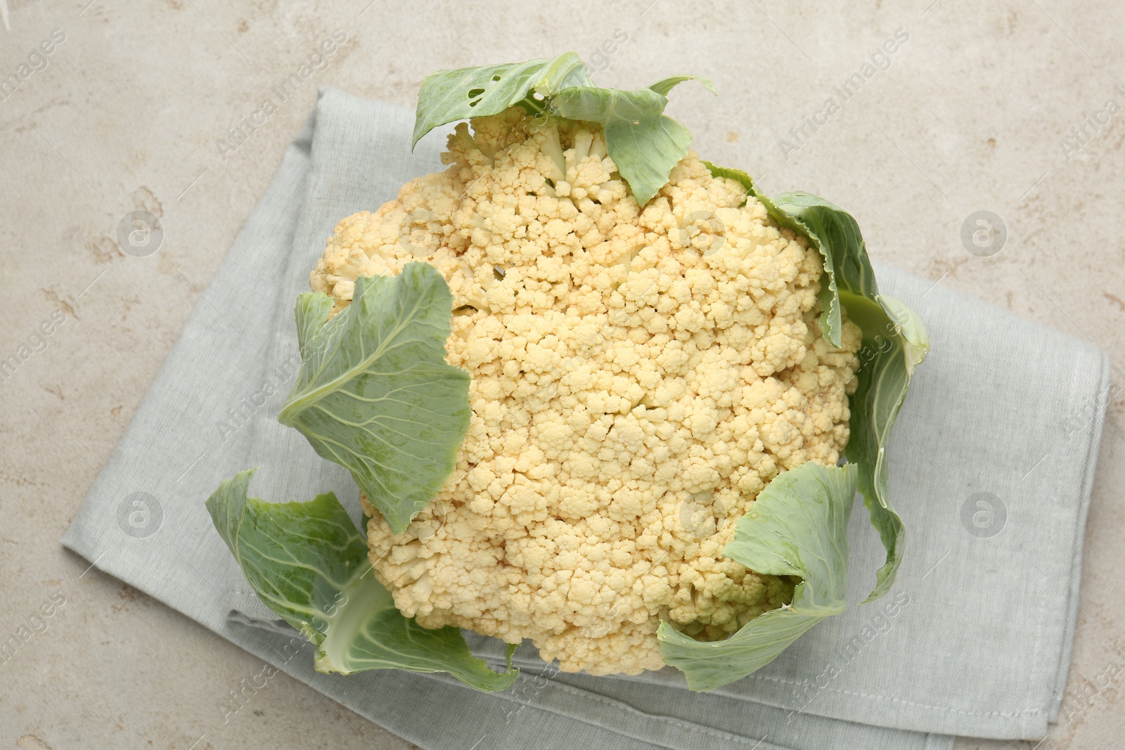 Photo of Fresh cauliflower with green leaves on light grey table, top view