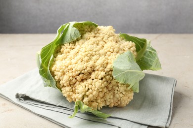 Photo of Fresh cauliflower with green leaves on light grey table, closeup