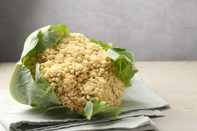 Photo of Fresh cauliflower with green leaves on light grey table, closeup. Space for text