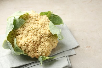 Photo of Fresh cauliflower with green leaves on light grey table, closeup. Space for text