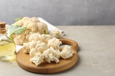 Photo of Fresh raw cauliflower florets and oil on light grey table, closeup. Space for text