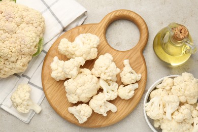 Photo of Fresh raw cauliflower florets and oil on light grey table, flat lay