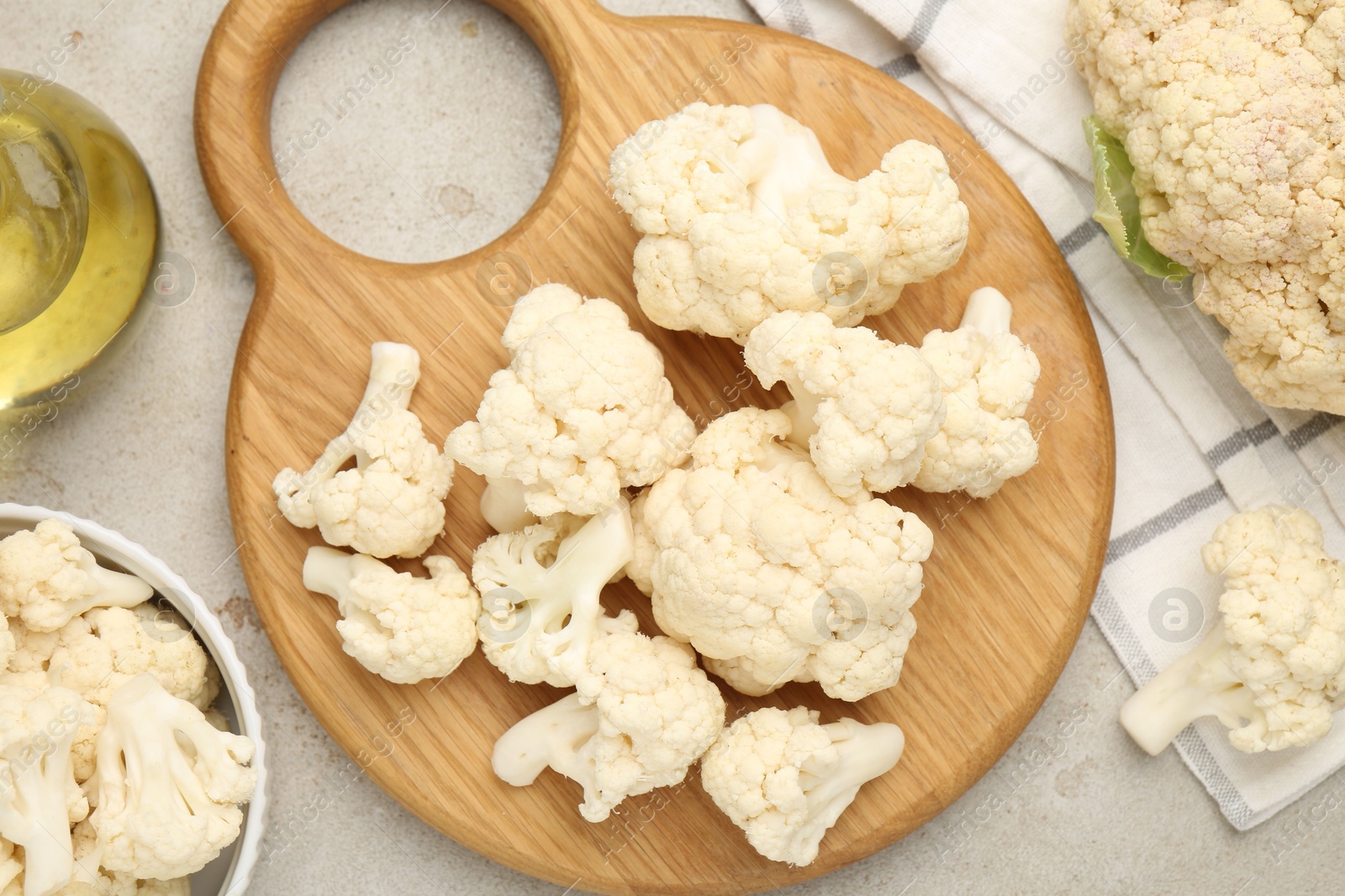 Photo of Fresh raw cauliflower florets and oil on light grey table, flat lay