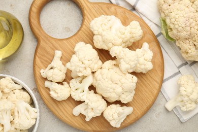 Photo of Fresh raw cauliflower florets and oil on light grey table, flat lay