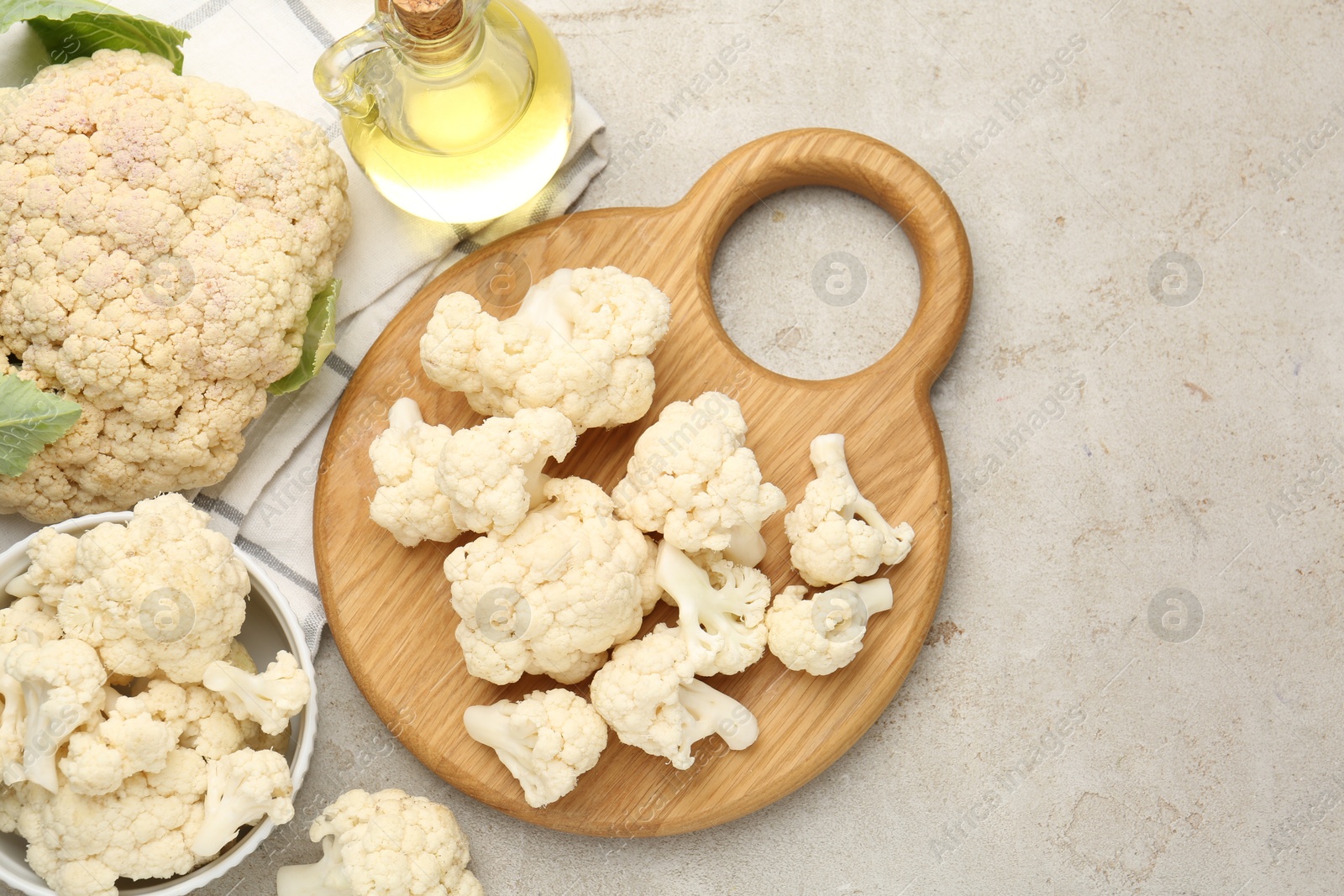 Photo of Fresh raw cauliflower florets and oil on light grey table, flat lay. Space for text