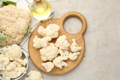 Photo of Fresh raw cauliflower florets and oil on light grey table, flat lay. Space for text