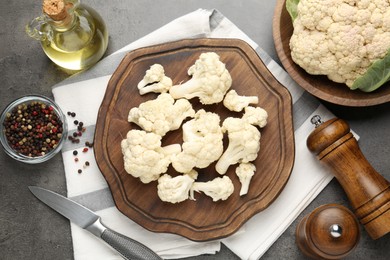 Photo of Fresh raw cauliflower florets, spices and knife on grey table, flat lay