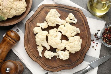 Photo of Fresh raw cauliflower florets, spices and knife on grey table, flat lay