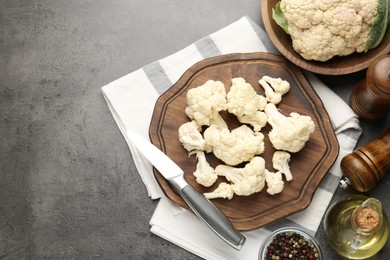 Photo of Fresh raw cauliflower florets, spices and knife on grey table, flat lay. Space for text