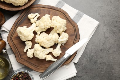 Photo of Fresh raw cauliflower florets, spices and knife on grey table, flat lay. Space for text