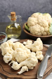 Photo of Fresh raw cauliflower florets, spices and knife on table, closeup