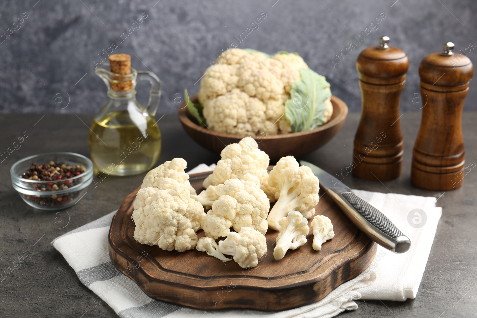 Fresh raw cauliflower florets, spices and knife on grey table, closeup Photo of Fresh raw cauliflower florets, spices and knife on grey table, closeup