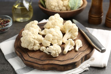 Photo of Fresh raw cauliflower florets, spices and knife on grey table, closeup