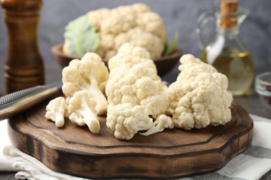 Photo of Fresh raw cauliflower florets, knife and spices on table, closeup