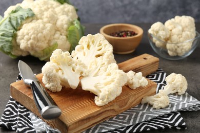 Photo of Fresh raw cauliflower florets, spices and knife on grey table, closeup