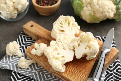 Photo of Fresh raw cauliflower florets, spices and knife on grey table, closeup