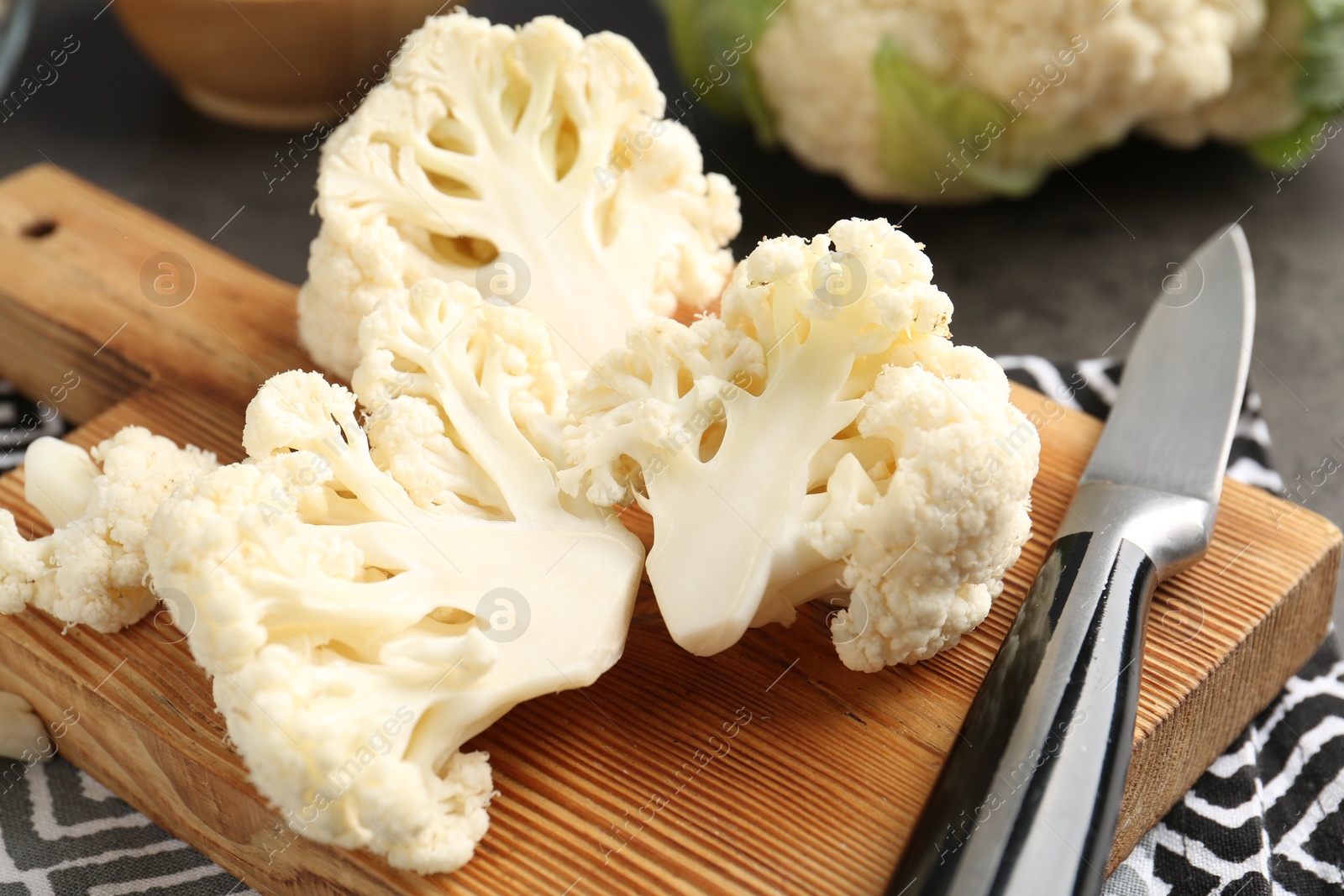 Photo of Fresh raw cauliflower florets and knife on table, closeup
