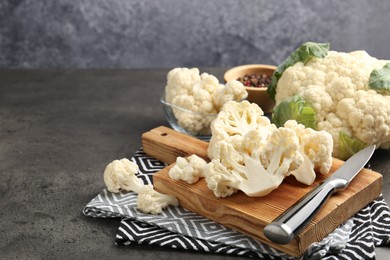 Photo of Fresh raw cauliflower florets, spices and knife on grey table, closeup. Space for text