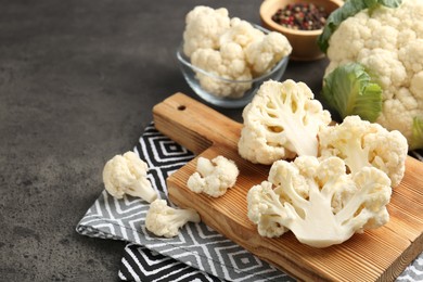 Photo of Fresh raw cauliflower florets and spices on grey table, closeup. Space for text